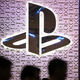A PlayStation logo is displayed at an event as people walk by.